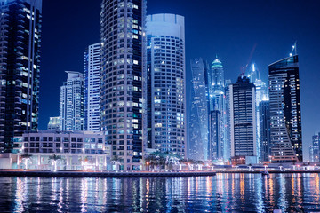 Big city lights. Night cityscape of Dubai marina embankment with skyscraper.