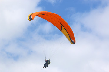 Tandem paraglider flying orange wing