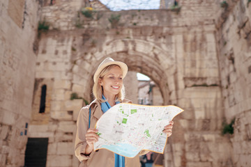 Travel and active lifestyle concept. Young traveller woman walking in ancient town holding tourist map.