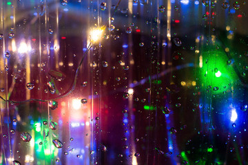 Macro photo of water droplets on a transparent surface in the backlight of multi-colored blurred lights. Abstract textural photo for background. Texture of water droplets in bright light for design.