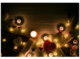 Candles burning among beautiful Christmas lights and garland decorations. New Year festive background. Presents, gifts, greeting postcard for winter holidays.
