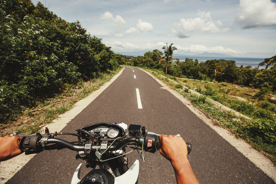 Biker driving motorcycle rides along the asphalt road, sea shore view