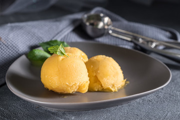 Mango ice cream sorbet with mint leaves on rustic background