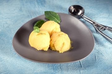 Mango ice cream sorbet with mint leaves on rustic background