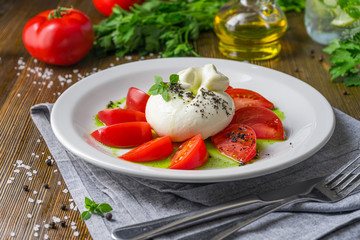 Fragrant tomatoes with the buratto on an old wooden table
