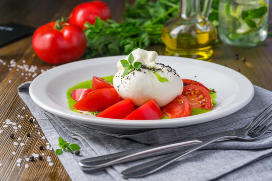 Fragrant tomatoes with the buratto on an old wooden table