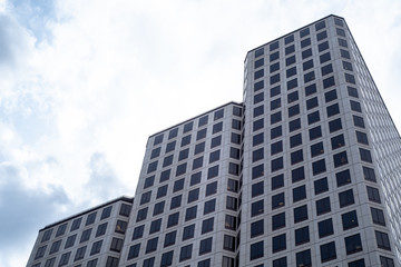 Fototapeta premium Low Angle Of Modern Glass Skyscraper Against Vivid Blue Sky with Clouds