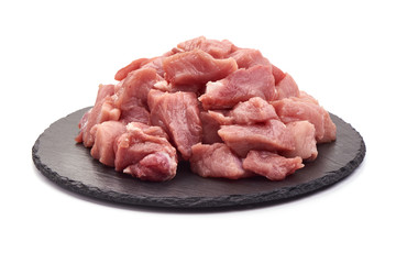 Raw pork pieces on a slate shale plate, close-up, isolated on white background