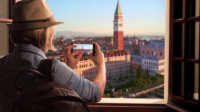 tourist takes photo of venice skyline at sunrise,traveler woman photographs st mark square using smartphone