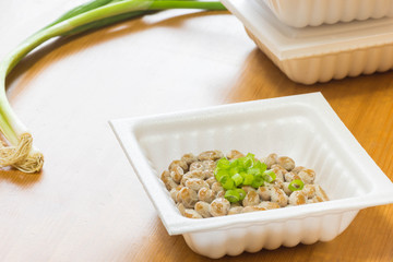 Natto - a popular and healthy Japanese food from fermented beans in a Styrofoam container with green spring onions as toppings. 