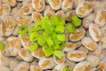 Natto - a popular and healthy Japanese food from fermented beans in a Styrofoam container with green spring onions as toppings. 