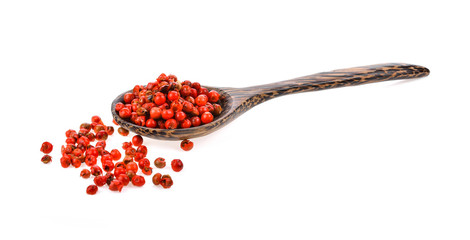 dried pink peppers in wood spoon isolated on white background