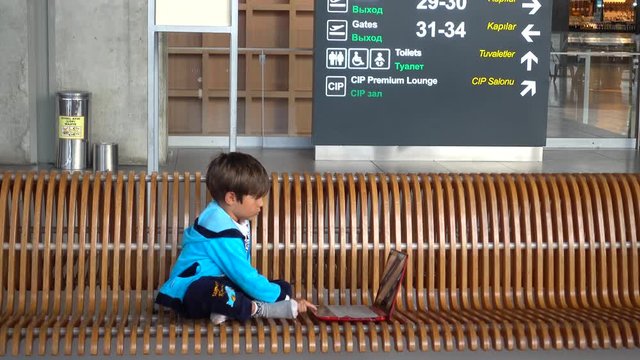 Dalaman Airport, Turkey - 24th of May 2018: 4K While waiting in the airport lounge a small kid plays with laptop, Crystal child