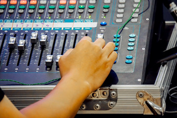 Closeup hand of technician sliding buttons of music equalizer and sound music mixer control panel in concert.