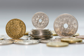 A ten, one and five krone coin standing on a pile of other Danish coins. The krone is the official currency of Denmark, Greenland, and the Faroe Islands, introduced on 1 January 1875.