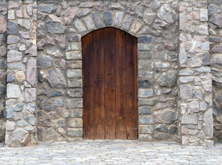 Fototapeta na wymiar stone wall and wooden door of an ancient castle. Fantasy, fairy tale, history, middle ages