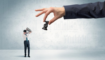 Little businessman is afraid to make the next step in his chess game with graphs, charts and...
