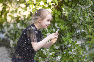 a little girl takes pictures on a smartphone