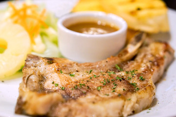Closeup and crop t-bone pork steak and garlic bread, decorate salads with pepper sauce on white ceramic plate and fit to screen.