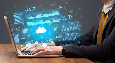 Businessman hand typing on laptop with reports and graphs concept around
