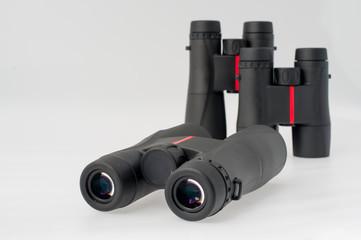 Three binoculars in different sizes with red details on a white background.