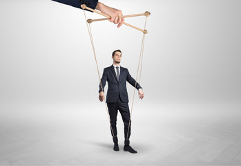Puppet businessman in an empty room leaded by a huge hand
