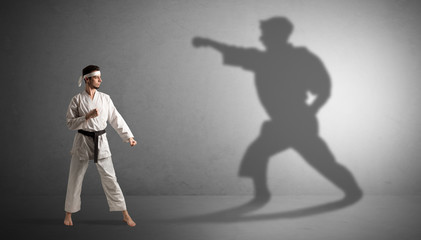 Young karate man confronting with his own shadow
