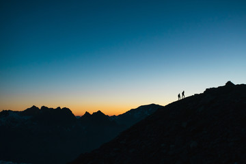 Two hikers silhouetted against the sky at sunset. - 268484032