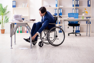 Young male employee in wheelchair working in the office 