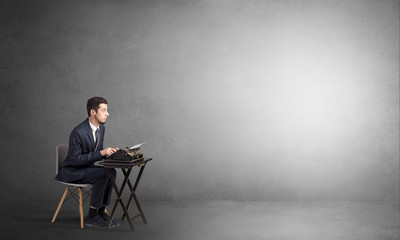 Man working hard on a typewriter in an empty space
