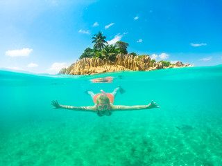 Split view of female apnea underwater and paradisiacal landscape of St. Pierre Island coral reef in...