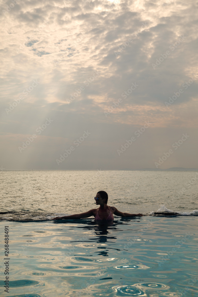 Wall mural sexy woman relaxing in the pool with infinity edge