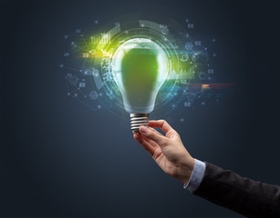 Hand holding light bulb on dark background. New business idea concept