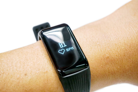 Closeup human's hand wear black healthy smart band with numbers and icon of hearth rate and pulse display on screen isolate on white background. - Powered by Adobe