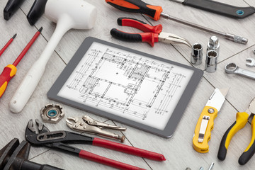Tablet with construction tools and blueprint concept

