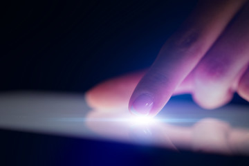 Finger touching tablet with dark background with copyspace
