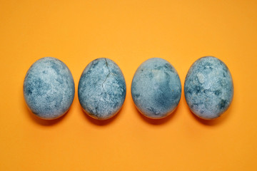 Four blue eggs, painted in tea hibiscus, on orange background, similar to planet and marble with copyspace