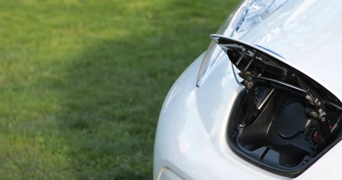 Electric vehicle zero emission charging port connection hand renewable energy car cable with white socket fully green drive modern eco clean transport easy to connect