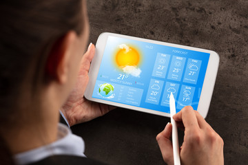 Business woman checking weekly weather forecast on tablet
