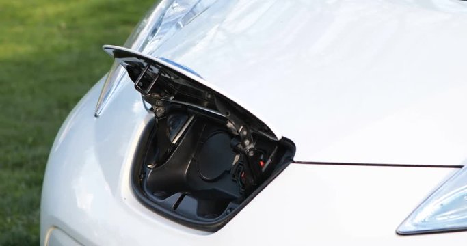 Electric vehicle zero emission charging port connection hand renewable energy car cable with white socket fully green drive modern eco clean transport easy to connect
