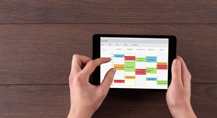 Hand holding tablet with timetable and calendar concept

