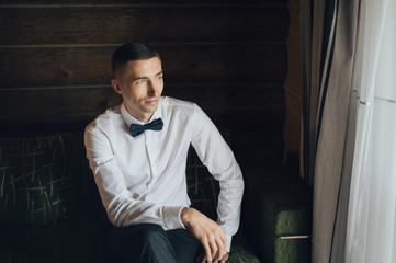 Portrait of Handsome groom getting dressed in a wedding shirt. 
