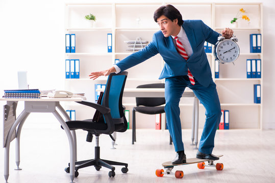 Young handsome businessman with longboard in the office 