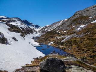 Fototapeta na wymiar Nature waking up after the hibernation process. Snow covering the mountains slowly melts, turning into countless ponds and small lakes. Barren landscape, Rocky and steep slopes of the mountains.