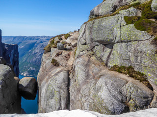 A dare-devil rock, Kjerag, Norway. The ball-shaped rock is hanging in between two steep stone walls with a free fall of 1000m. Behind it there is Lysefjorden. Bright and clear day.