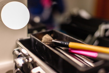 brushes for a make-up in a suitcase at a mirror in a dressing room