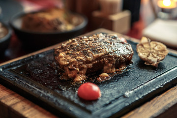 Hot appetizing beef steak served on a stone slab. Food concept. American cuisine. Dinner at restaurant