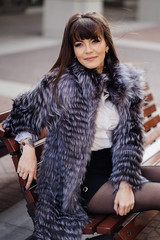 beautiful brunette with the long straight hair wearing in a grey fur coat, white shirt and black...