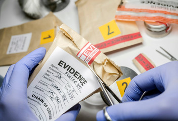 Scientific police opens with scissors a bag of evidence of a crime in scientific laboratory