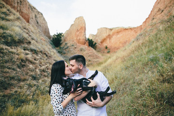 Outdoor portrait of young pregnant couple and a dog in field
